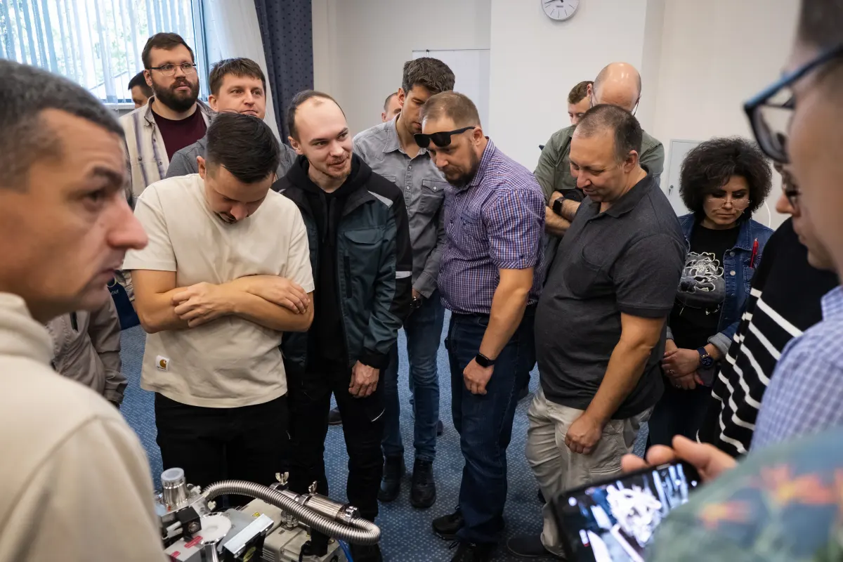 Course participants studying vacuum and helium leak testing equipment during field mentoring