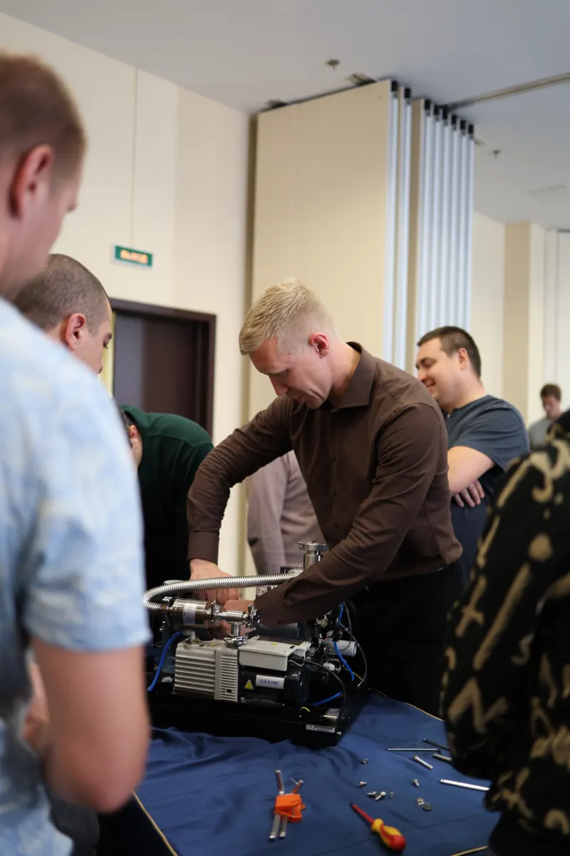 Course participants working hands-on with a helium leak detector during VacMentor training